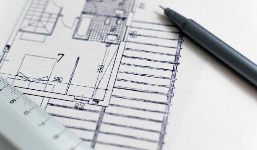 Imagem mostra uma folha de papel na cor branca com o desenho de um projeto de Arquitetura. Há também uma lapiseira e uma régua na imagem.