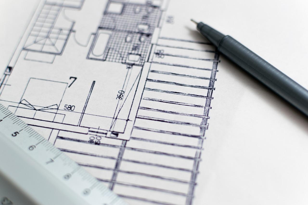 Imagem mostra uma folha de papel na cor branca com o desenho de um projeto de Arquitetura. Há também uma lapiseira e uma régua na imagem.