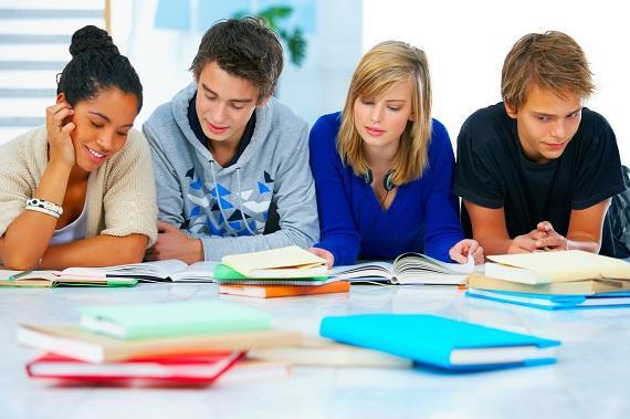 O que é um curso profissionalizante? Descubra agora! - Imagem mostra quatro estudantes sentados em frente à mesa lendo alguns papéis